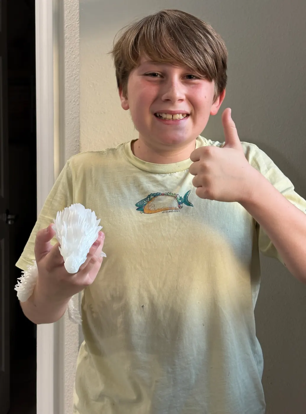 Young maker holding a dragon print and giving a thumbs-up